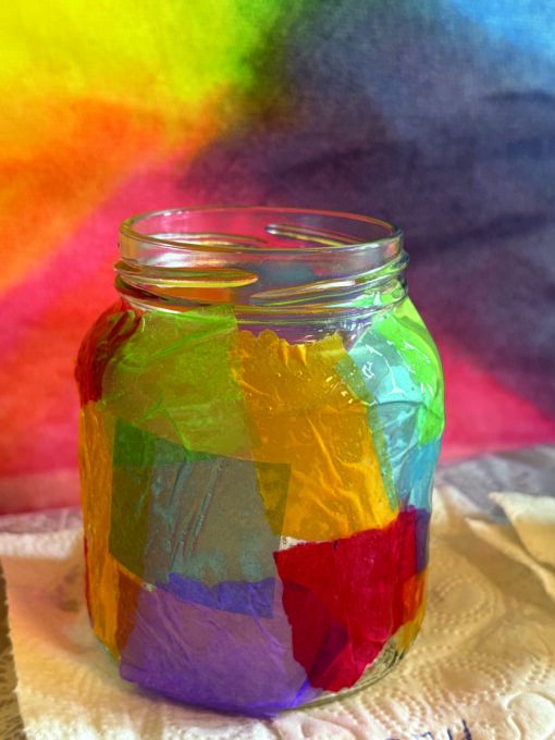 Ein Einmachglas ist mit bunten Transparentpapierstücken beklebt.