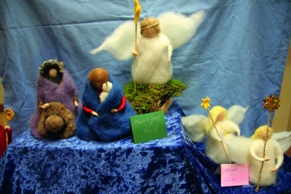 Gefilzte Engel und weihnachtliche Figuren auf einem blauen Samttuch und vor einem blauen Hintergrund.